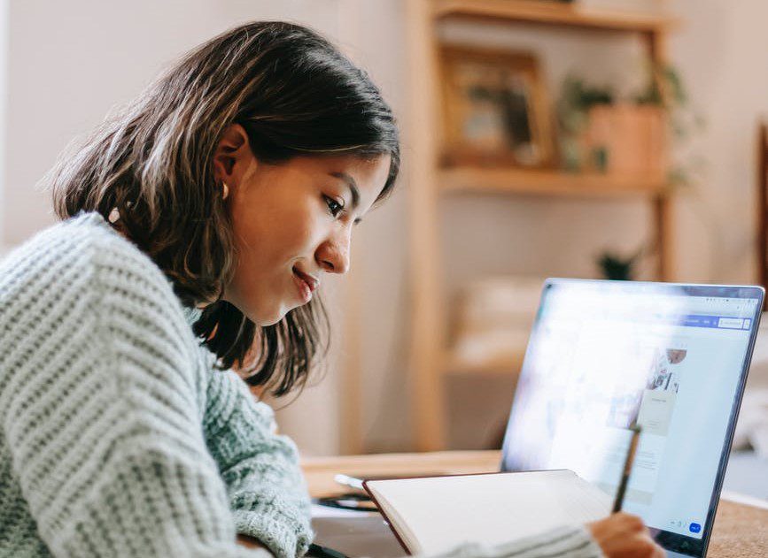woman writing in journal for linkedin learning course, business skills